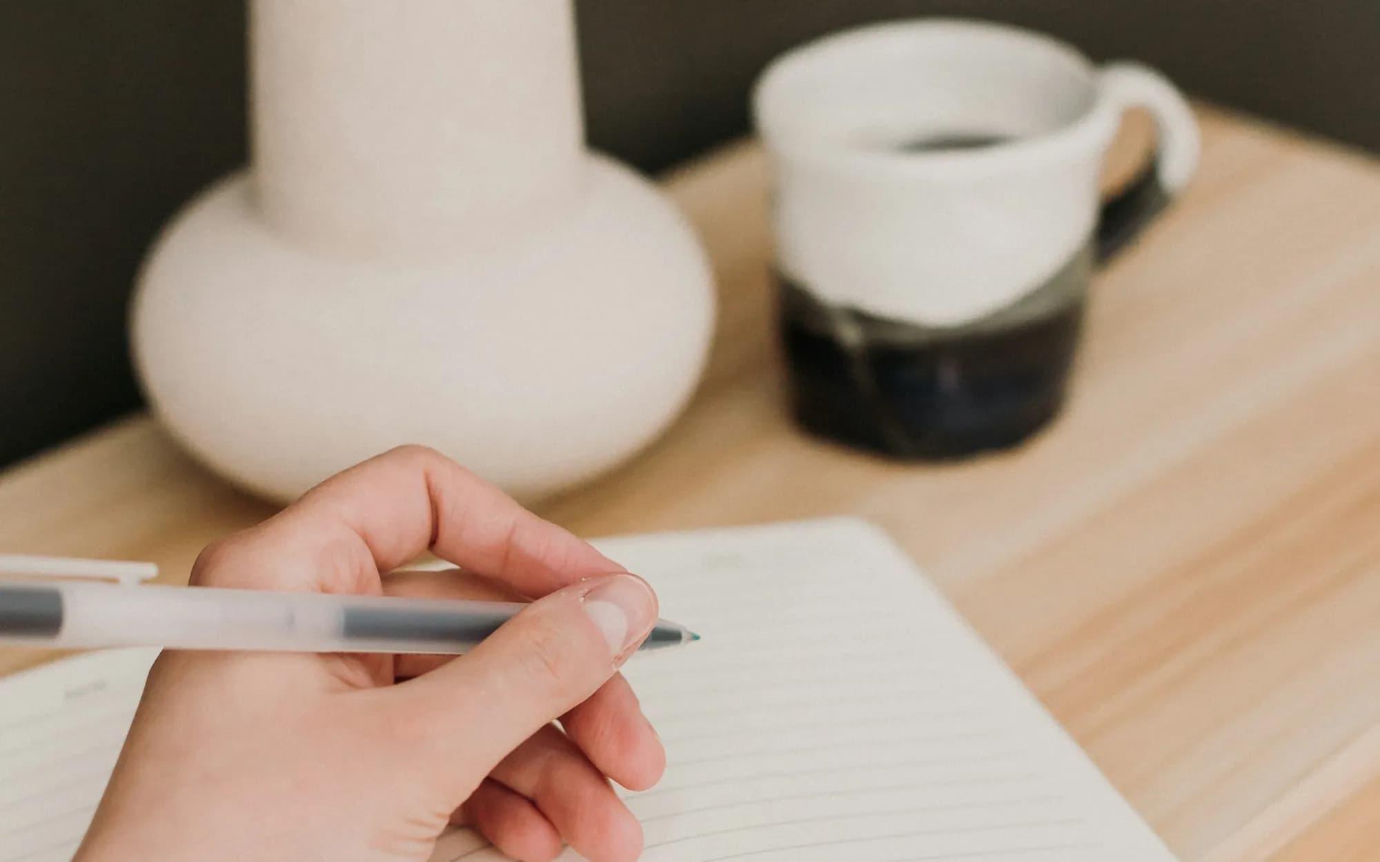 Hand writing a weekly update in a notebook